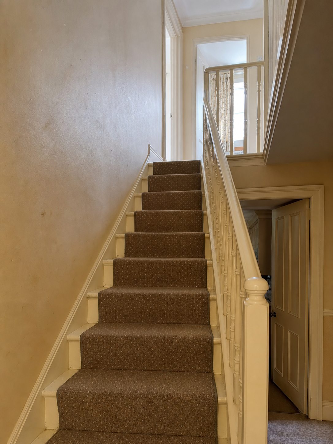 AI-generated concept of a dated hall and staircase before decorating, with scuffed beige walls and dull cream woodwork